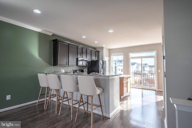 kitchen with a breakfast bar, kitchen peninsula, stainless steel fridge, and dark hardwood / wood-style flooring