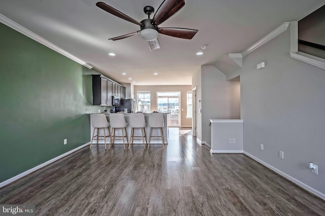 kitchen featuring ceiling fan, dark hardwood / wood-style floors, kitchen peninsula, a kitchen bar, and stainless steel fridge