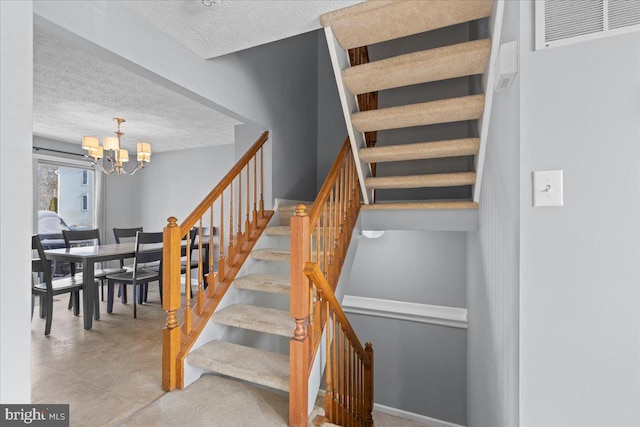 stairway featuring a textured ceiling and an inviting chandelier