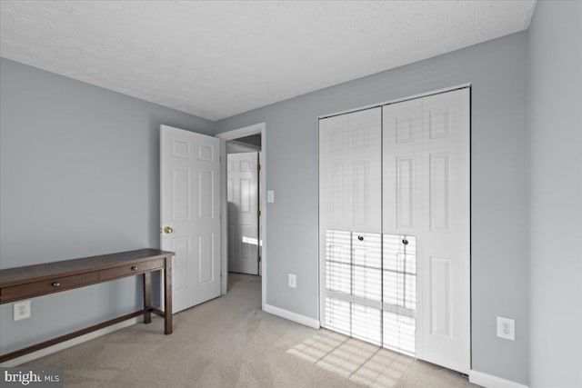 unfurnished bedroom featuring a textured ceiling, a closet, and light colored carpet