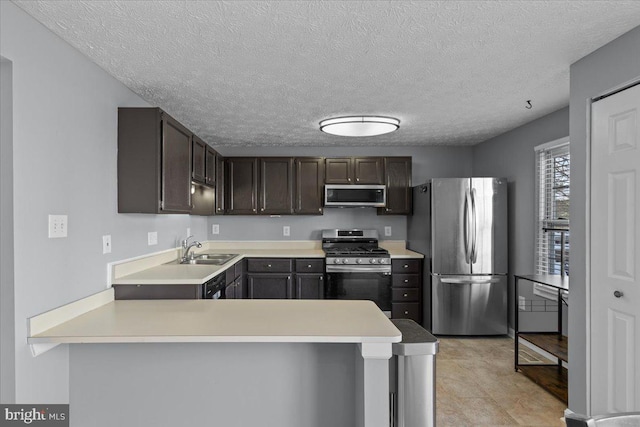 kitchen with kitchen peninsula, sink, dark brown cabinetry, a textured ceiling, and stainless steel appliances