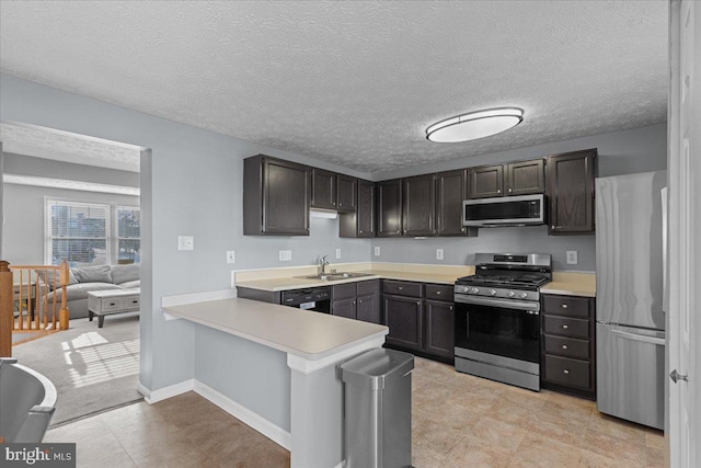 kitchen with a textured ceiling, stainless steel appliances, sink, kitchen peninsula, and dark brown cabinets