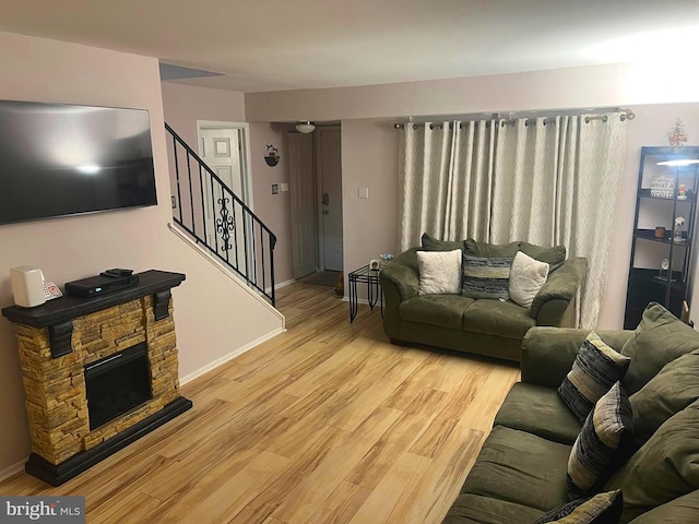 living room with a stone fireplace and light hardwood / wood-style flooring