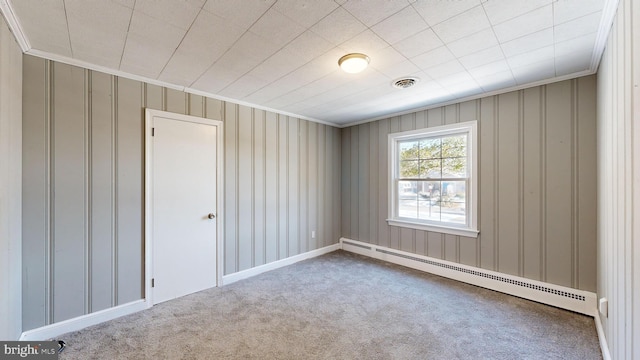 empty room featuring a baseboard heating unit, ornamental molding, and carpet flooring