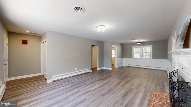 unfurnished living room featuring a baseboard heating unit, visible vents, light wood-style floors, and a fireplace with flush hearth