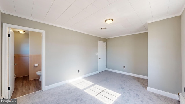 carpeted spare room featuring crown molding and tile walls