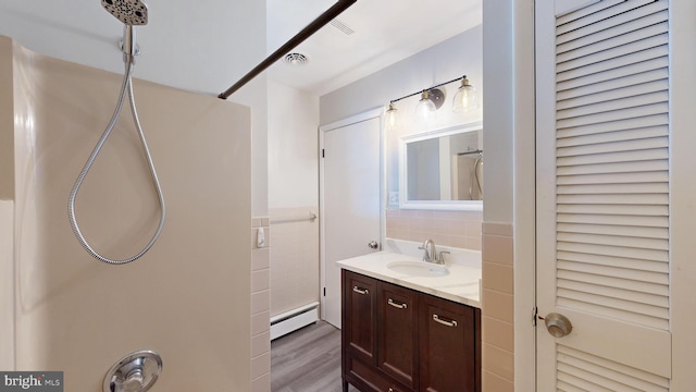 bathroom with wood-type flooring, vanity, and a baseboard radiator