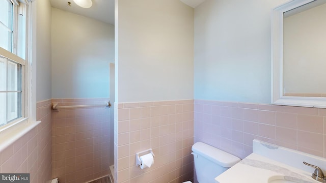 bathroom featuring toilet, tile walls, and vanity