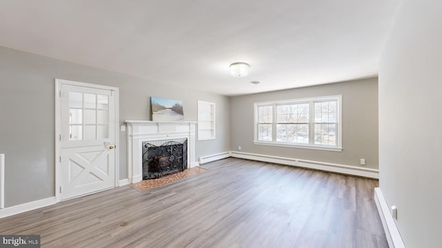 unfurnished living room with a baseboard heating unit and hardwood / wood-style floors