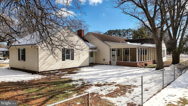 snow covered rear of property with a porch