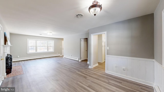 unfurnished living room with a baseboard heating unit and light hardwood / wood-style floors