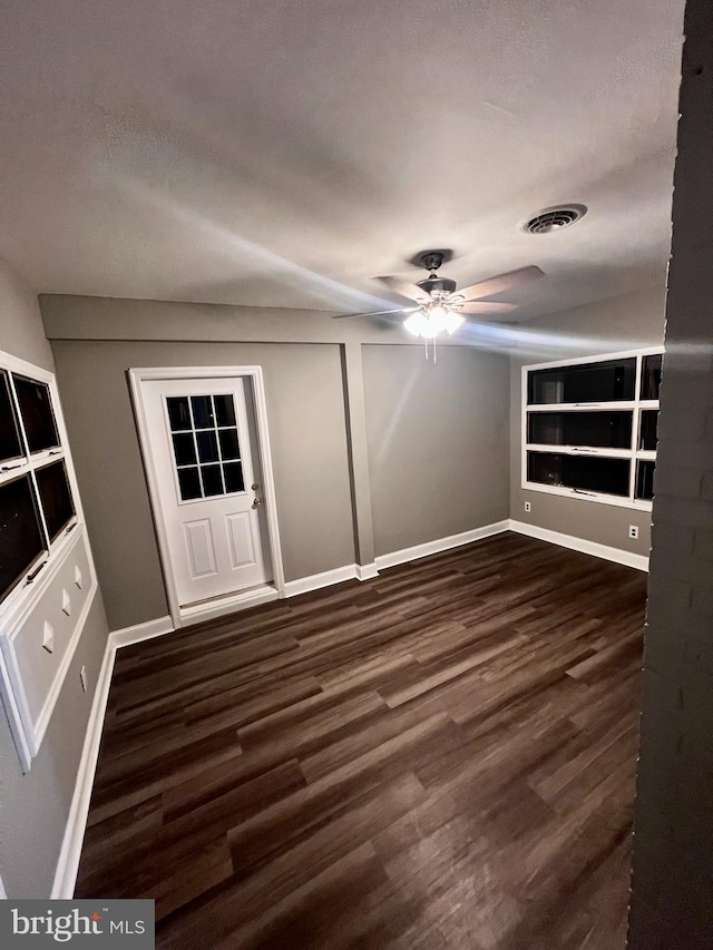 interior space featuring visible vents, dark wood finished floors, baseboards, and ceiling fan