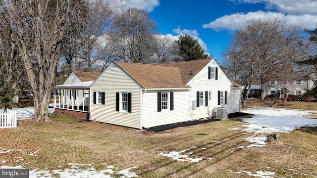 exterior space featuring central air condition unit, a shingled roof, and a lawn