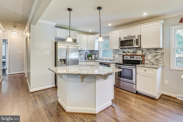 kitchen with a kitchen island, decorative backsplash, white cabinetry, appliances with stainless steel finishes, and light stone counters