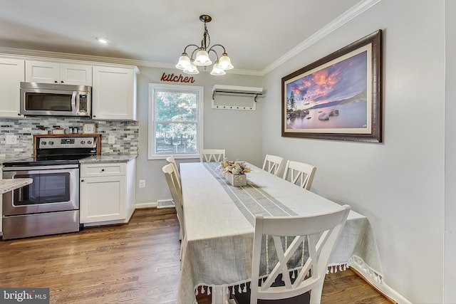 dining room featuring an inviting chandelier, crown molding, and hardwood / wood-style floors