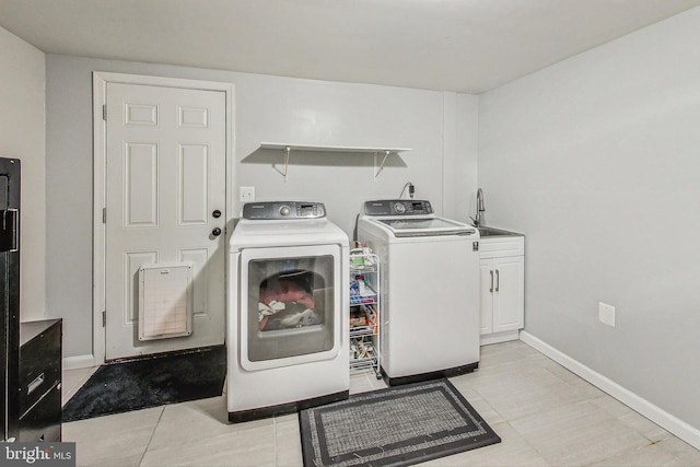 laundry room featuring light tile patterned flooring, cabinets, washer and dryer, and sink