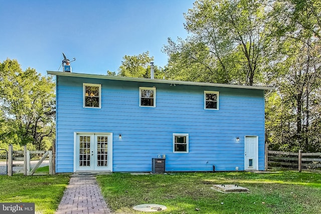 rear view of property with a lawn, french doors, and central AC