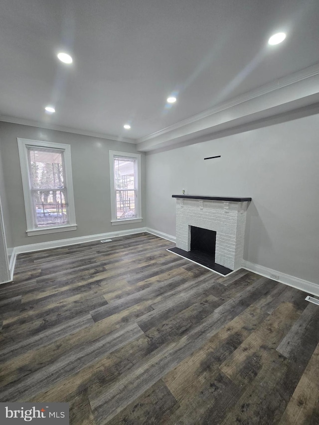 unfurnished living room featuring dark hardwood / wood-style flooring, ornamental molding, and a fireplace