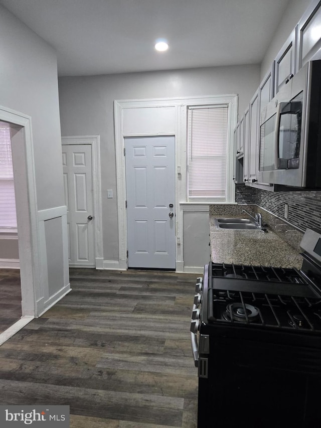 kitchen featuring tasteful backsplash, dark hardwood / wood-style floors, sink, stainless steel appliances, and dark stone counters