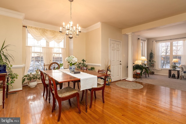 dining area with an inviting chandelier, light hardwood / wood-style floors, and ornate columns