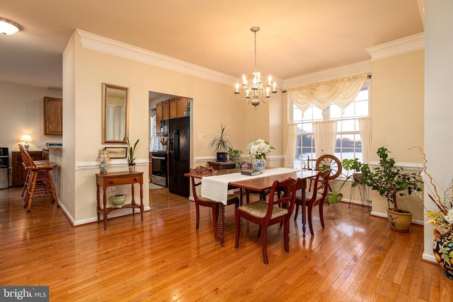 dining area with crown molding, a chandelier, and light wood-type flooring