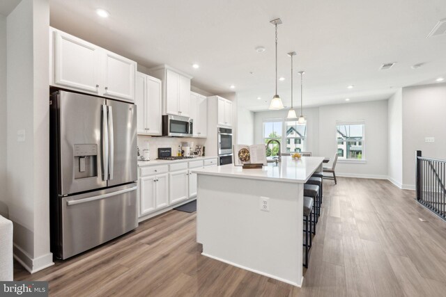 14079 Sunrise Valley Dr Unit 15P, Herndon, VA 20171 - kitchen featuring stainless steel appliances, light wood-style flooring, white cabinets, a kitchen island with sink, and recessed lighting