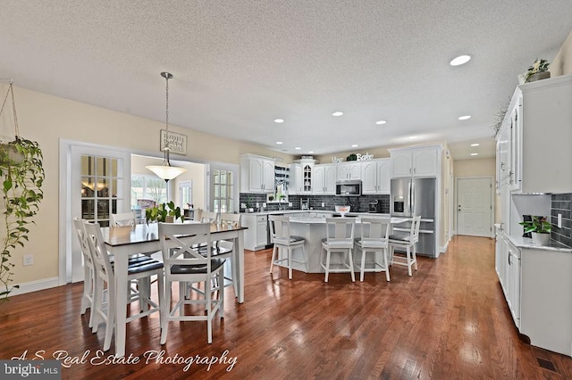 kitchen featuring white cabinets, a kitchen island, stainless steel appliances, hanging light fixtures, and a breakfast bar area