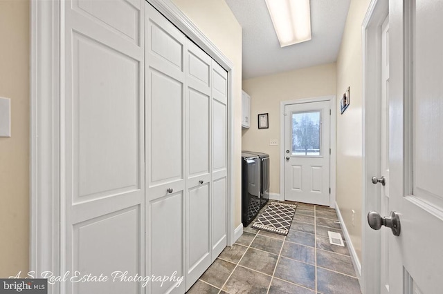 interior space with cabinets, washer and dryer, and dark tile patterned flooring