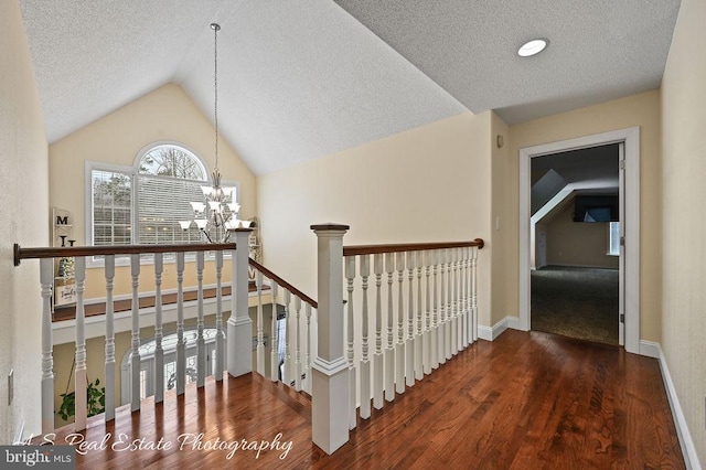 stairs with a textured ceiling, an inviting chandelier, vaulted ceiling, and hardwood / wood-style floors