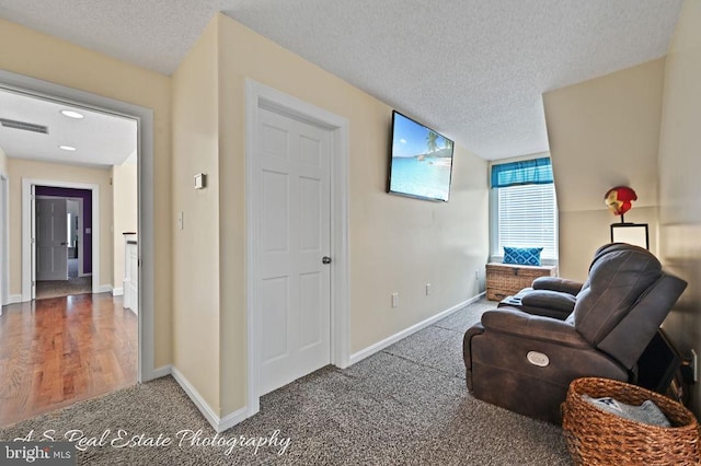 living area featuring a textured ceiling and carpet floors