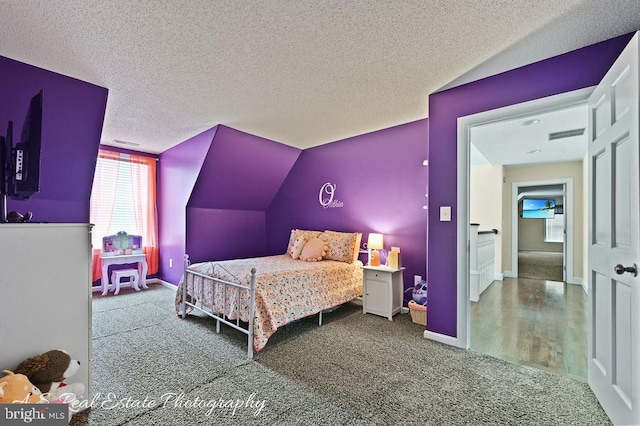 bedroom with vaulted ceiling, carpet flooring, and a textured ceiling