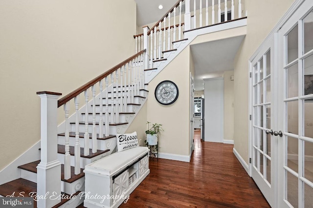 stairway with french doors, a towering ceiling, and hardwood / wood-style floors