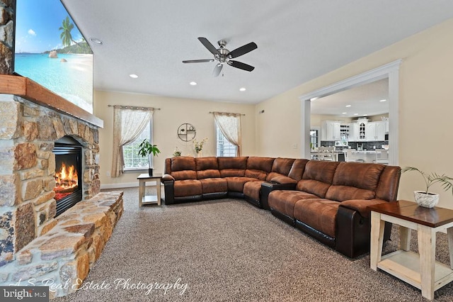 carpeted living room with a water view, ceiling fan, and a fireplace