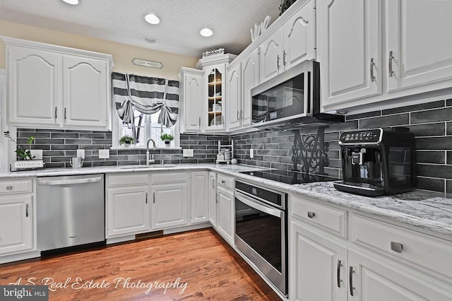 kitchen with appliances with stainless steel finishes, decorative backsplash, white cabinetry, and sink