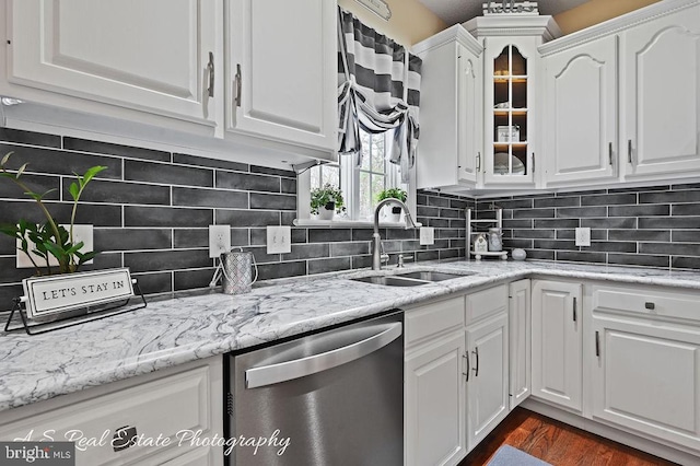 kitchen with stainless steel dishwasher, sink, tasteful backsplash, and white cabinetry