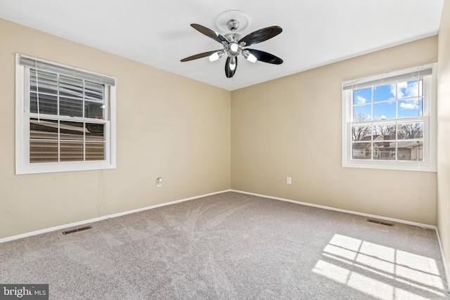 carpeted empty room featuring baseboards, visible vents, and a ceiling fan