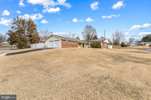 ranch-style home with a garage, driveway, brick siding, fence, and a front yard