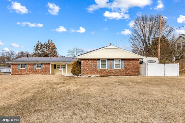 ranch-style house featuring a front yard, fence, and brick siding