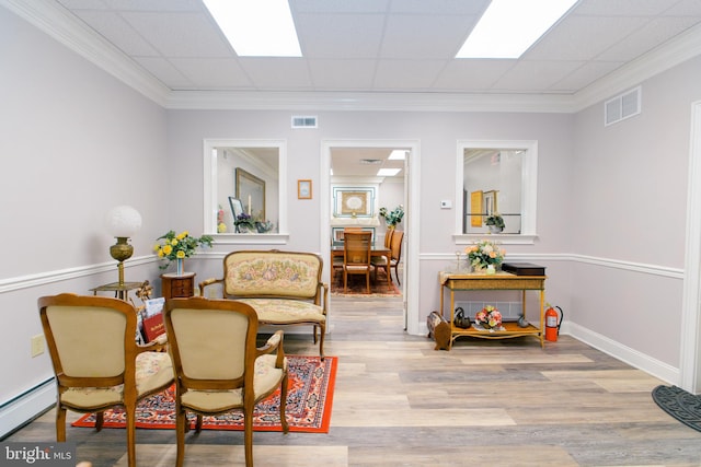 sitting room featuring crown molding, light hardwood / wood-style floors, a drop ceiling, and a baseboard radiator