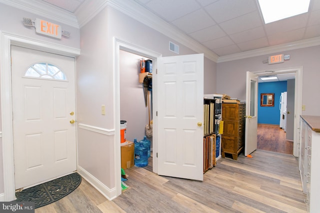 foyer entrance with light wood-type flooring, ornamental molding, and a drop ceiling