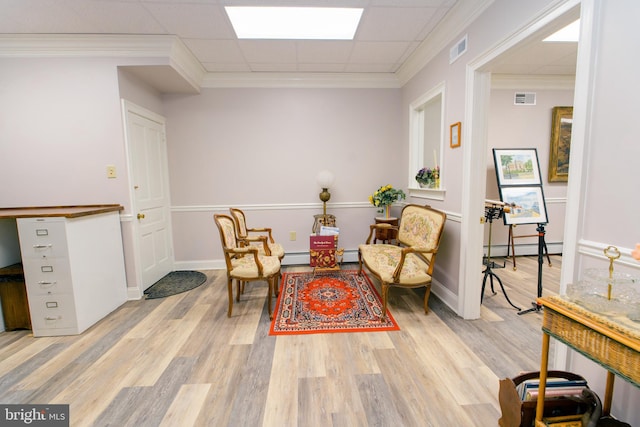 sitting room with a baseboard radiator, a paneled ceiling, ornamental molding, and light wood-type flooring