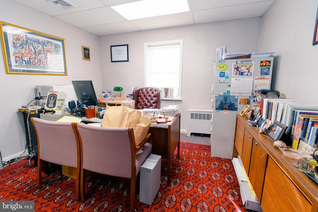 office space with a drop ceiling and radiator