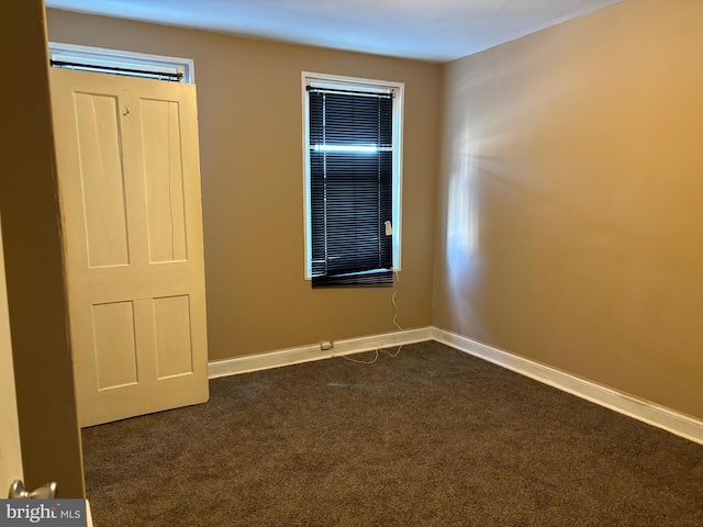 spare room featuring dark carpet