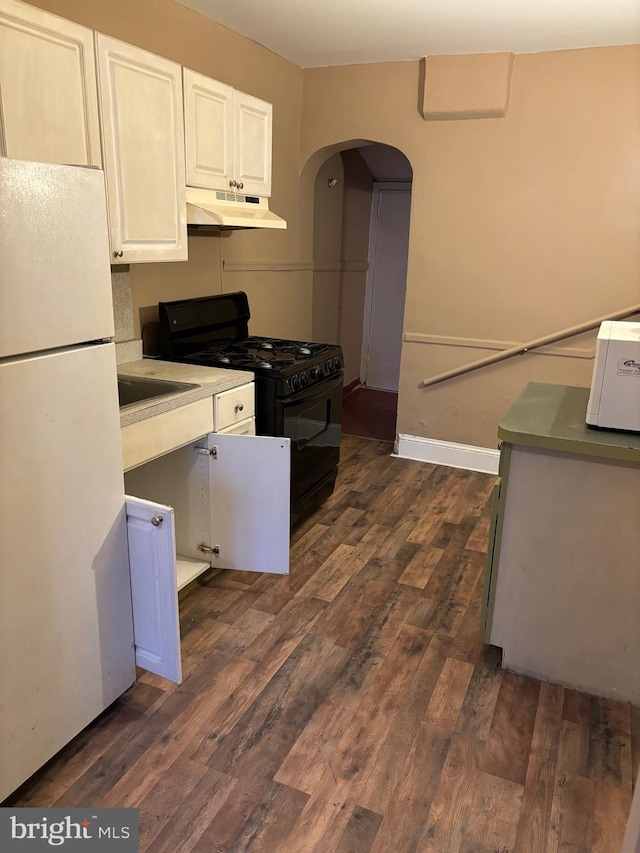 kitchen featuring white cabinets, gas stove, dark wood-type flooring, white refrigerator, and sink