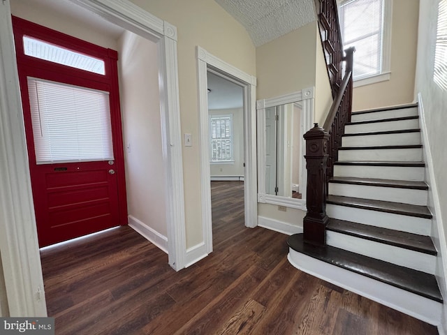 entrance foyer with vaulted ceiling, baseboard heating, plenty of natural light, and dark hardwood / wood-style floors