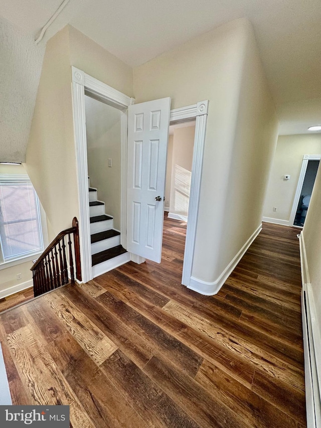 stairs with hardwood / wood-style floors and a baseboard radiator