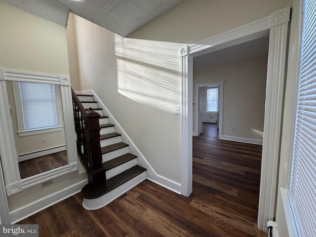 stairway featuring wood-type flooring, baseboard heating, and a textured ceiling