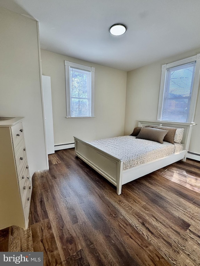 bedroom with a baseboard heating unit and dark hardwood / wood-style floors