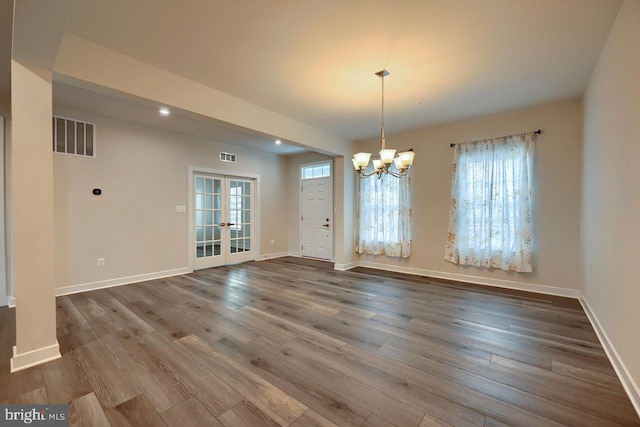 unfurnished dining area with a chandelier, wood-type flooring, and french doors