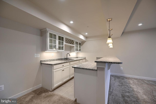 kitchen with decorative light fixtures, white cabinetry, a kitchen breakfast bar, sink, and kitchen peninsula